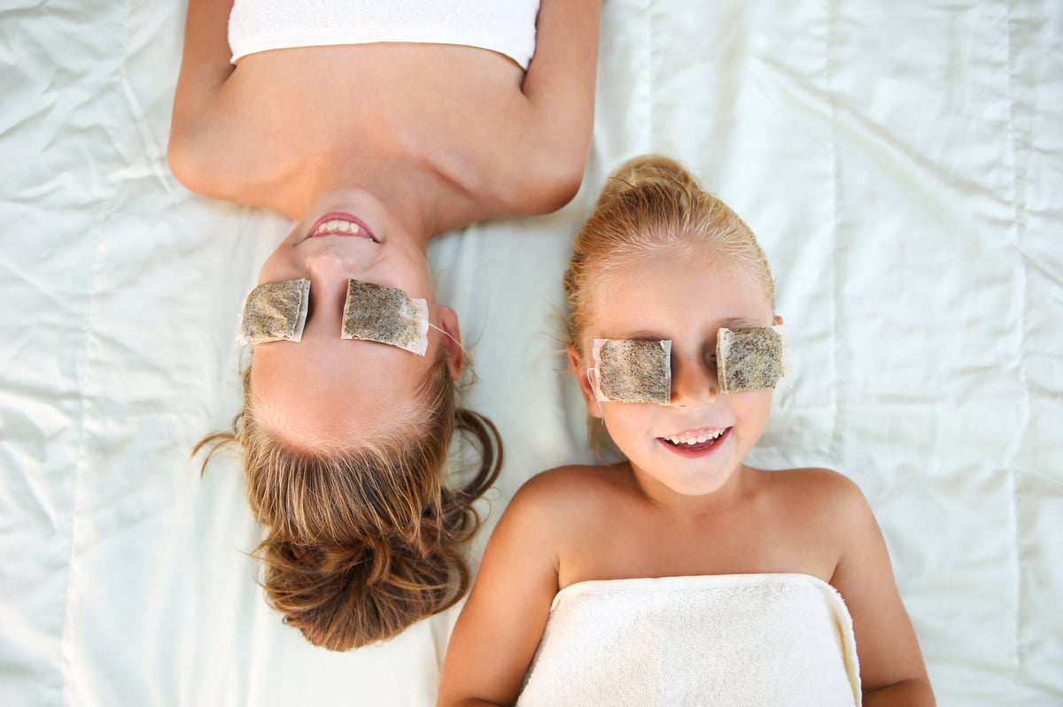 Beautiful girls with tea bags on eyes. Top view.