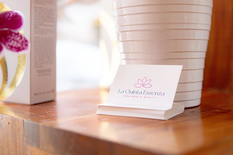 Business card with lotus logo on wooden desk surrounded by wellness product packaging and flowers