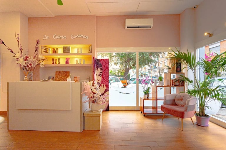 Modern salon interior with reception desk, illuminated shelving, floral arrangements, seating area, and large front windows overlooking street